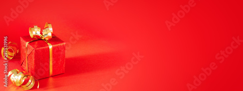 Red gift box with golden bow and streamers on red background. Minimal styled ...