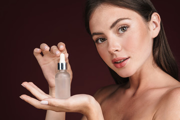 Canvas Print - Image of half-naked woman holding serum bottle and looking at camera