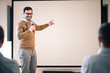 © bnenin - Portrait of a speaker on a seminar, talking on microphone and pointing at blank screen.