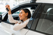 © LIGHTFIELD STUDIOS - cheerful young woman holding car key while sitting in car