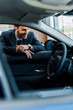 © LIGHTFIELD STUDIOS - selective focus of happy bearded man looking at modern car
