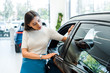 © LIGHTFIELD STUDIOS - attractive woman looking at modern auto in car showroom