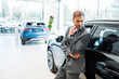 © LIGHTFIELD STUDIOS - pensive bearded businessman standing near cars in car showroom