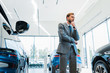 © LIGHTFIELD STUDIOS - pensive bearded businessman standing near automobiles in car showroom