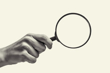 Female Hand Holding The Magnifying Glass On Isolated Background. Black And White Image.