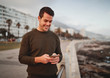 © StratfordProductions - Portrait of a happy attractive young man standing on city street texting massages on his smart phone