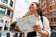 © Akaberka - Attractive young female tourist exploring european city. Woman with map in hands searching right direction on map.