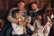 © Вячеслав Косько - Two married couples are friends. Together celebrate the New Year. Celebrate Christmas. Champagne in the hands of girls and boys. Against the background of a wooden house. Cozy atmosphere