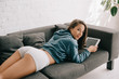 beautiful smiling woman in panties using digital tablet on sofa