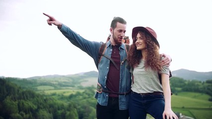 Wall Mural - young tourist couple travellers with backpacks hiking in nature, talking.