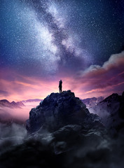 Wall Mural - night sky long exposure landscape. a man standing on a high rock watching the stars rise into the ni