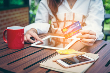 Close-up woman's hands holding a credit card and using computer keyboard for online shopping