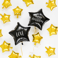 Wall Mural - Black and gold foil balloons of stars shaped. Holiday and celebration concept. Birthday Day or party decoration. Metallic air balloons..