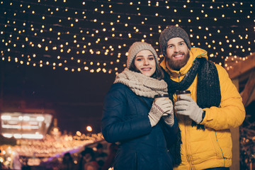 Photo of two people couple with hot tea beverage in hands celebrating x-mas eve night spend time magic outdoors newyear atmosphere park wearing warm jackets