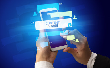 Female hand typing on smartphone with CONTENT IS KING inscription, social networking concept