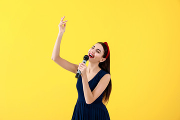 Wall Mural - Beautiful young female singer with microphone on color background