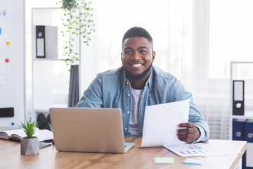 Aufkleber - Cheerful afro businessman working with laptop and documents in office