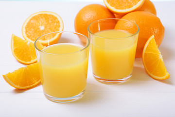 Orange juice in a glass, oranges and orange slices on the table.