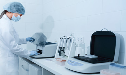 Poster - Young woman working in modern laboratory and using analyzer