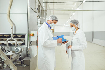 Technologists inspector in masks at food factory.