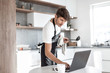 © ASDF - young man looking at laptop screen while cooking dinner