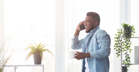Poster - Cheerful african american man talking on phone and drinking coffee