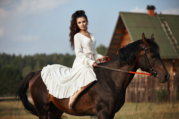 Girl in a long dress riding a horse, a beautiful woman riding a horse in a field in autumn. Country life and fashion, noble steed