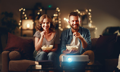 Wall Mural - Family couple watching television projector at home on sofa.