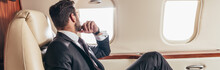 Panoramic Shot Of Businessman In Suit Looking Through Window In Private Plane
