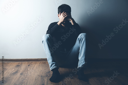 Fotografía sad man sitting on ground on dark background