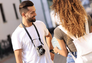 Poster - Young couple walking and looking at a guide while looking happy