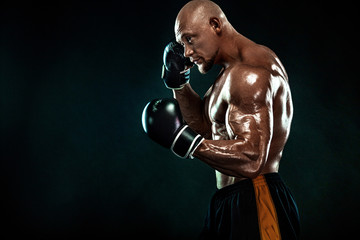 Sportsman, man boxer fighting in gloves on black background. Fitness and boxing concept. Individual sports recreation.