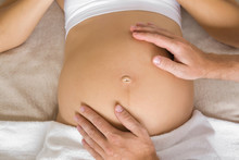 Man Hands Touching Pregnant Woman Belly. Lying Down On Bed. Breech Baby. Problems In Pregnancy Time. Close Up. Top Down View.