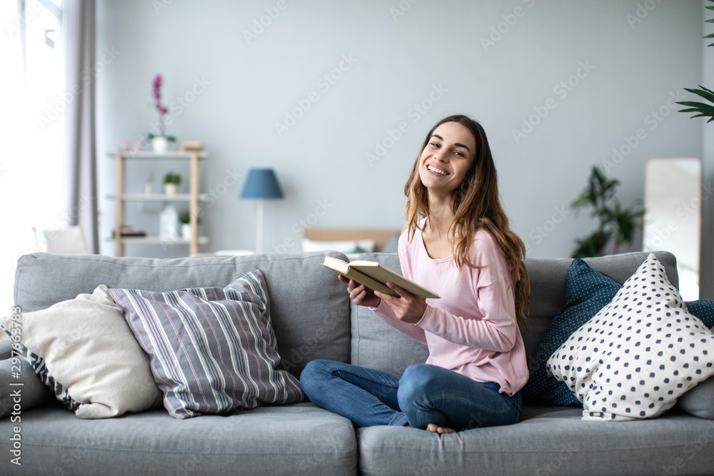 Beautiful female with a book and smiling looking camera. - obrazy, fototapety, plakaty 