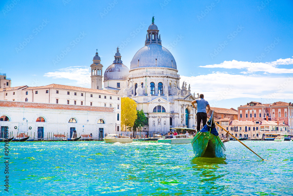 Gondolier and gondola on Grand Canal, Basilica Santa Maria della Salute in Venice, Italy. Sunny summer day with blue sky.  - obrazy, fototapety, plakaty 