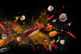 Hot red pepper, garlic, different spices powder meat stakes flying on a black background Motion freeze photo composition