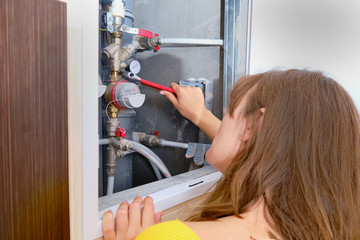 Woman with a wrench repairs water pipes in a riser