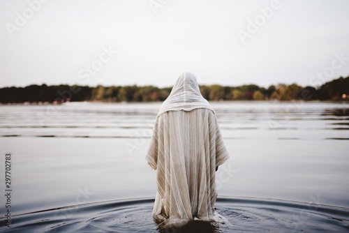 Cuadros en Lienzo Person wearing a biblical robe walking in the water with a blurred background sh