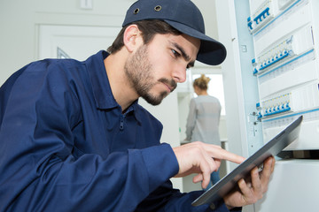 technician with digital tablet by residential fusebox