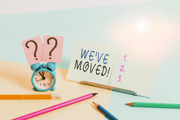 Writing note showing We Ve Moved. Business concept for To go from one residence or location to another Relocate Mini size alarm clock beside stationary on pastel backdrop