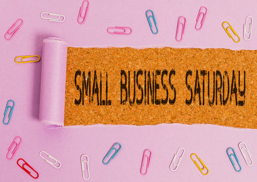 Word writing text Small Business Saturday. Business photo showcasing American shopping holiday held during the Saturday Paper clip and torn cardboard placed above a wooden classic table backdrop