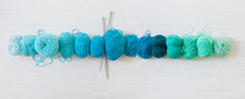 Yarn For Knitting Aquamarine, Green, Blue And Turquoise Colors. White Wood Long Background
