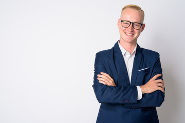 Happy young blonde businessman in suit smiling with arms crossed