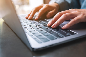 closeup image of a woman working and typing on laptop computer on the table