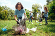 Volunteering. Young people volunteers outdoors asian girl picking litter close-up concentrated