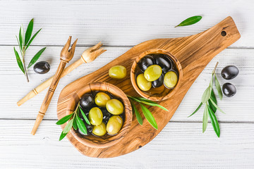 Wall Mural - Fresh green and black olives on white background. Olive mix in wooden bowl from top view on rustic board with copy space.