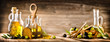 Leinwandbild Motiv Fresh olives in rustic bowls on old wooden table. Virgin olive oil in clear glass bottles copy space.  Panorama or banner concept.