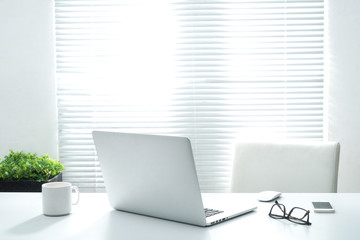 Office workplace with laptop and eye glasses on white table