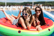 © F8  \ Suport Ukraine - Two women lying on inflatable watermelon mattrass floating and relaxing in swimming pool