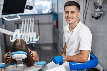 Wall Mural - Dental clinic. Reception, examination of the patient. Teeth care. Young woman undergoes a dental examination by a dentist.Happy patient and dentist concept.Male dentist in dental office talking with g